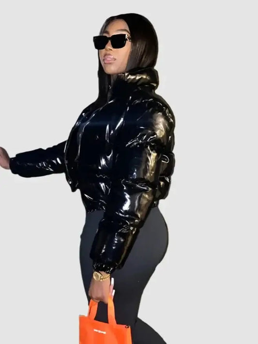 Woman in a shiny black Y2K cropped jacket with sunglasses and an orange handbag