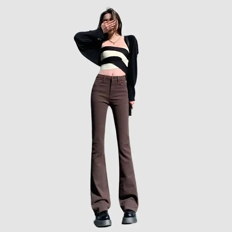 Woman modeling Y2K Flare Jeans with a striped crop top and black cardigan