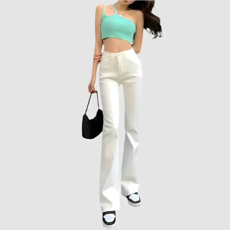 Woman in mint green crop top and white Y2K flare jeans with black handbag