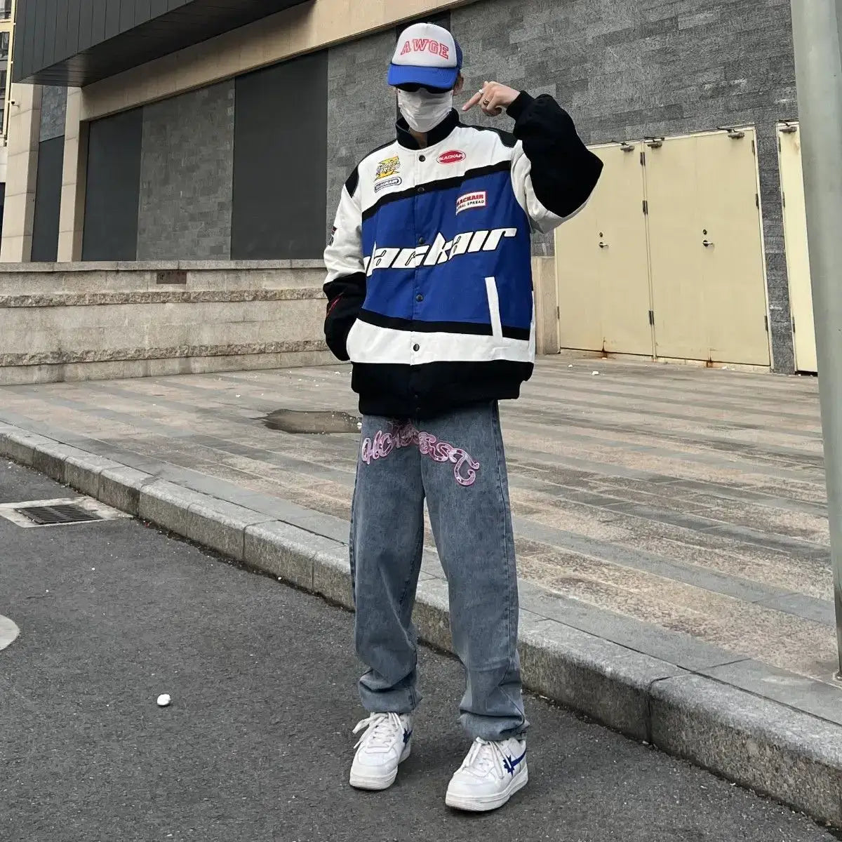 Person in blue and white racing-style jacket showcasing Y2K graphic jeans