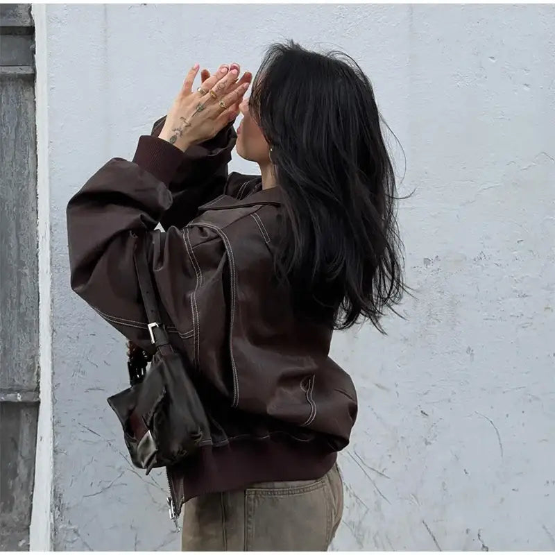 Brown leather jacket worn by a person with long dark hair, showcasing a Y2K style