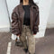 Oversized brown leather jacket over black top and beige pants, stylish Y2K leather jacket