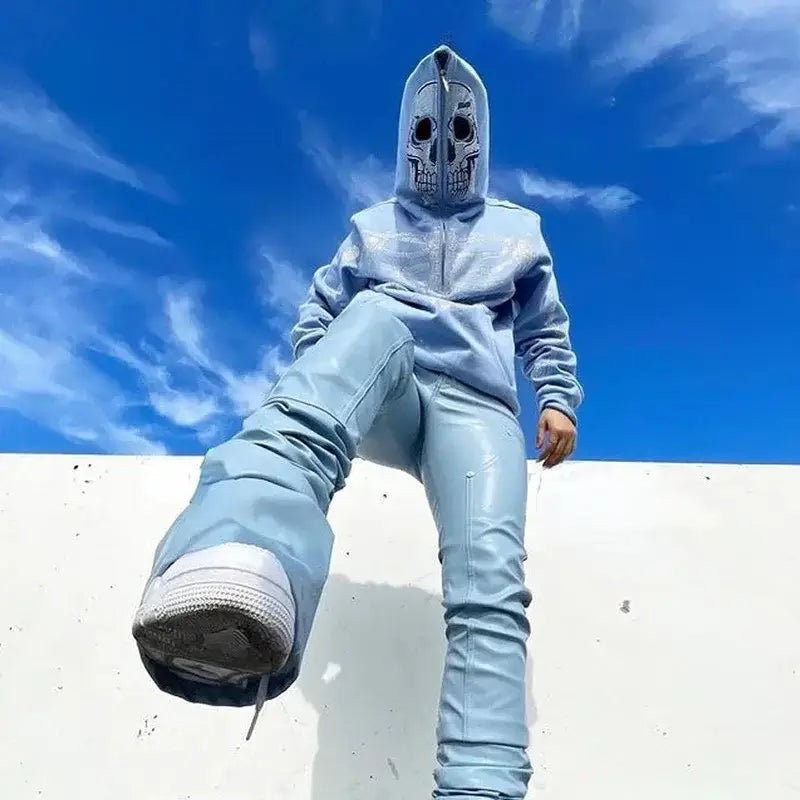 Person in a skull mask and light blue outfit showcasing Y2K Skull Hoodie on white surface