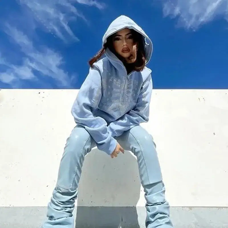 Woman in light blue Y2K Skull Hoodie and jeans sitting stylishly on a surface