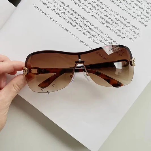 Pair of brown-tinted rimless Y2K style sunglasses with metal arms over a book page