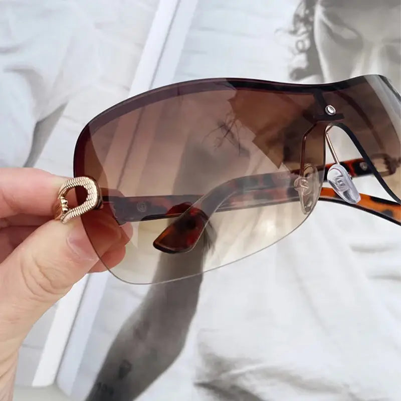 Pair of Y2K style sunglasses featuring a shield-style lens with gold accents