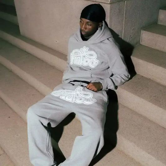 Person in gray Y2K sweat pants with white graphics sitting on concrete steps