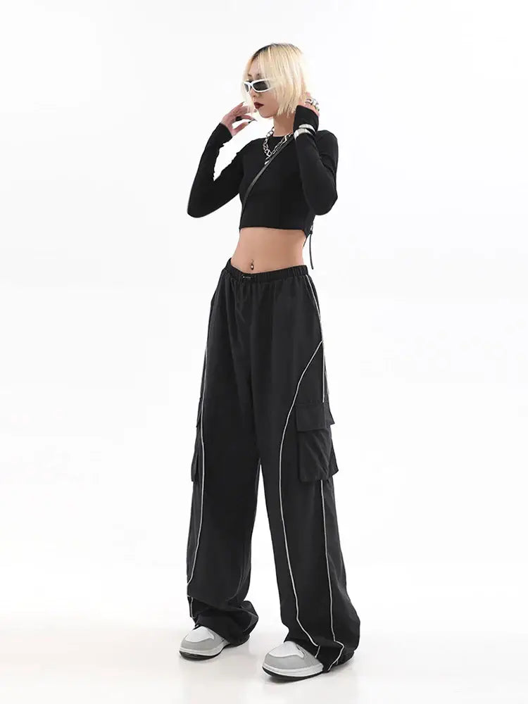 Woman in black crop top and wide-leg Y2K track pants with white trim