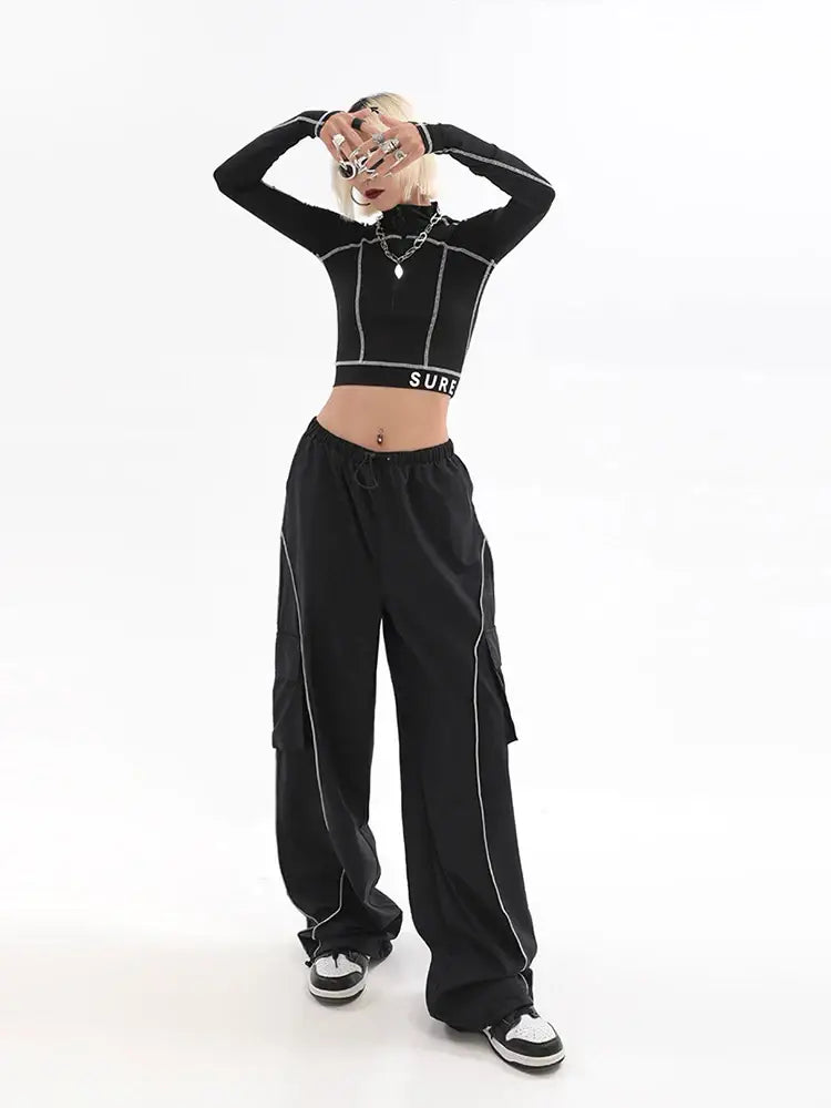 Woman in a black crop top and wide-leg Y2K Track Pants with white stitching details